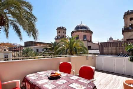 una mesa y sillas en un balcón con vistas a los edificios en Magic Atico in the heart of the old town, en Alicante