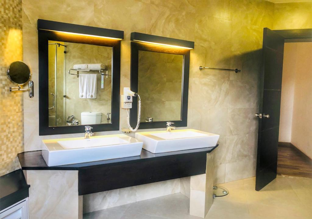 a bathroom with two sinks and two mirrors at The Blackpool Resort & Spa in Nuwara Eliya