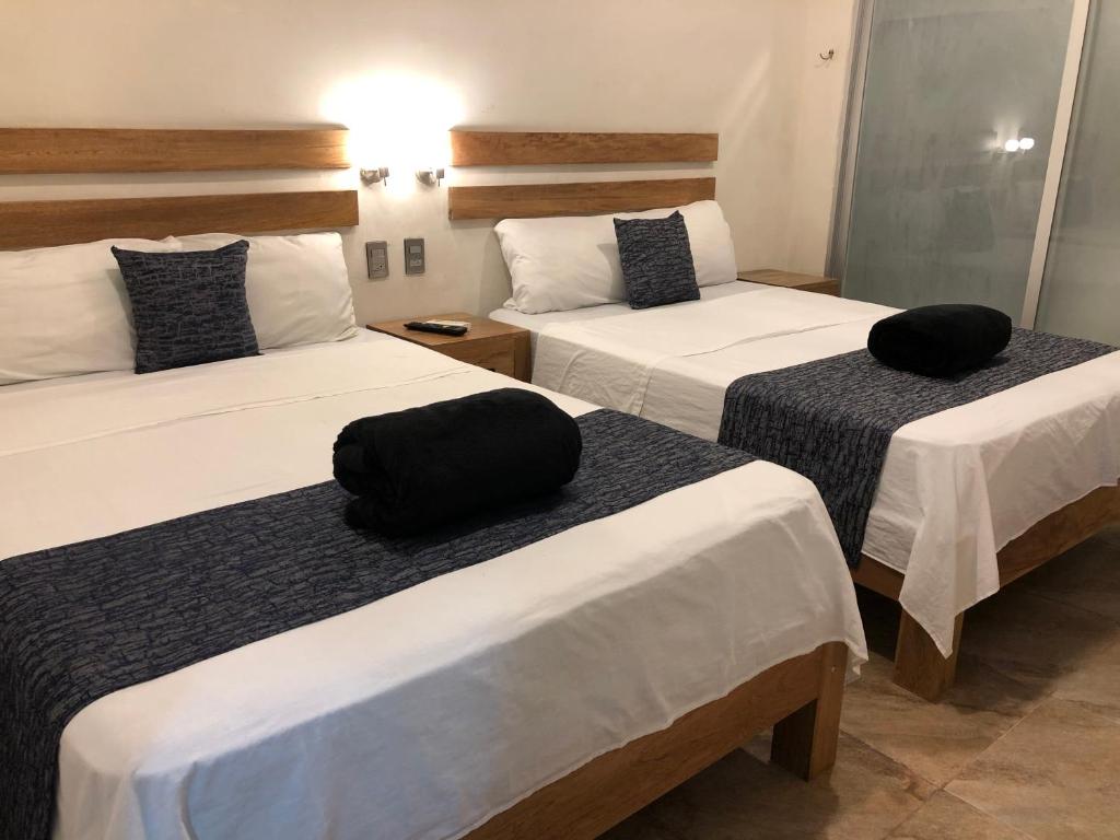 a hotel room with two beds with black pillows on them at 15 AVENIDA in Tapachula