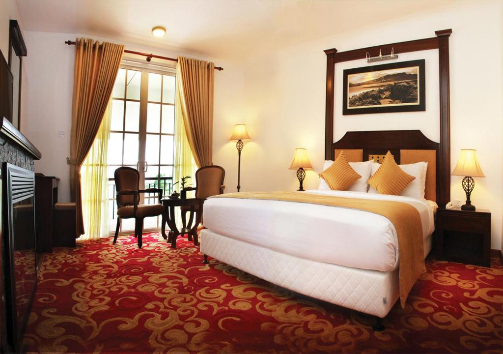 a hotel room with a large bed and a table at The Blackpool Resort & Spa in Nuwara Eliya