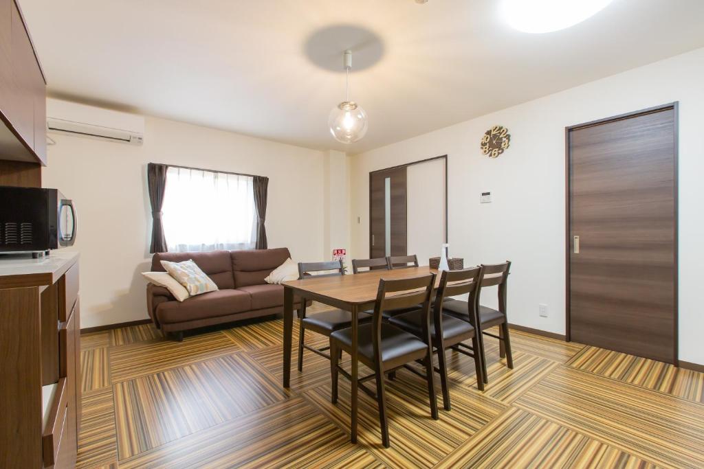 ein Wohnzimmer mit einem Tisch, Stühlen und einem Sofa in der Unterkunft Ryugu -竜宮- in Osaka