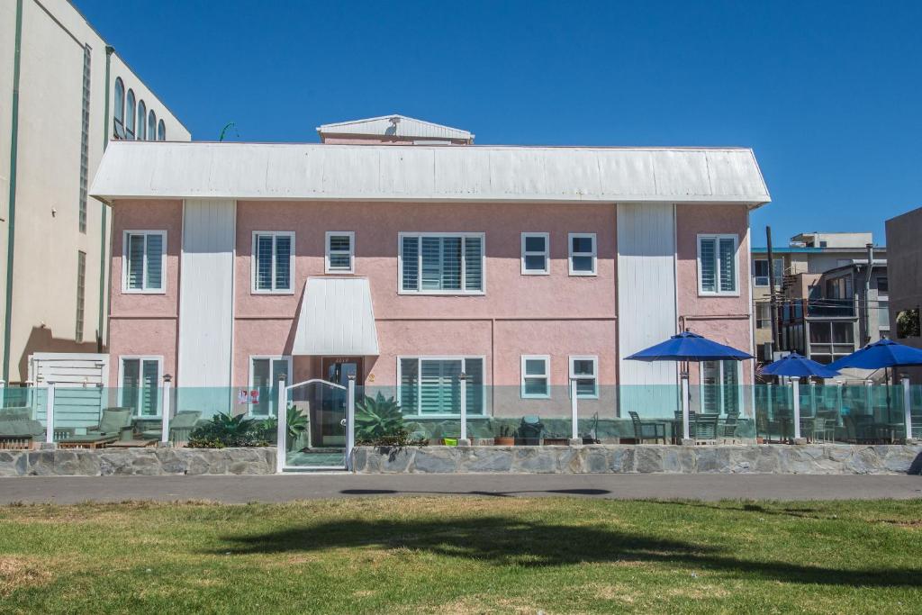 a pink and white building with umbrellas in front of it at Venice on the Beach Hotel in Los Angeles