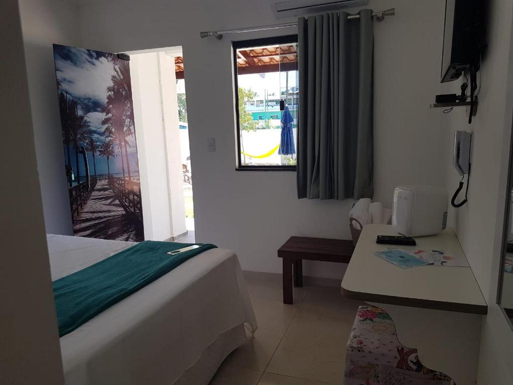 a bedroom with a bed and a table and a window at Residencial e Pousada Sea La Vie in Maragogi