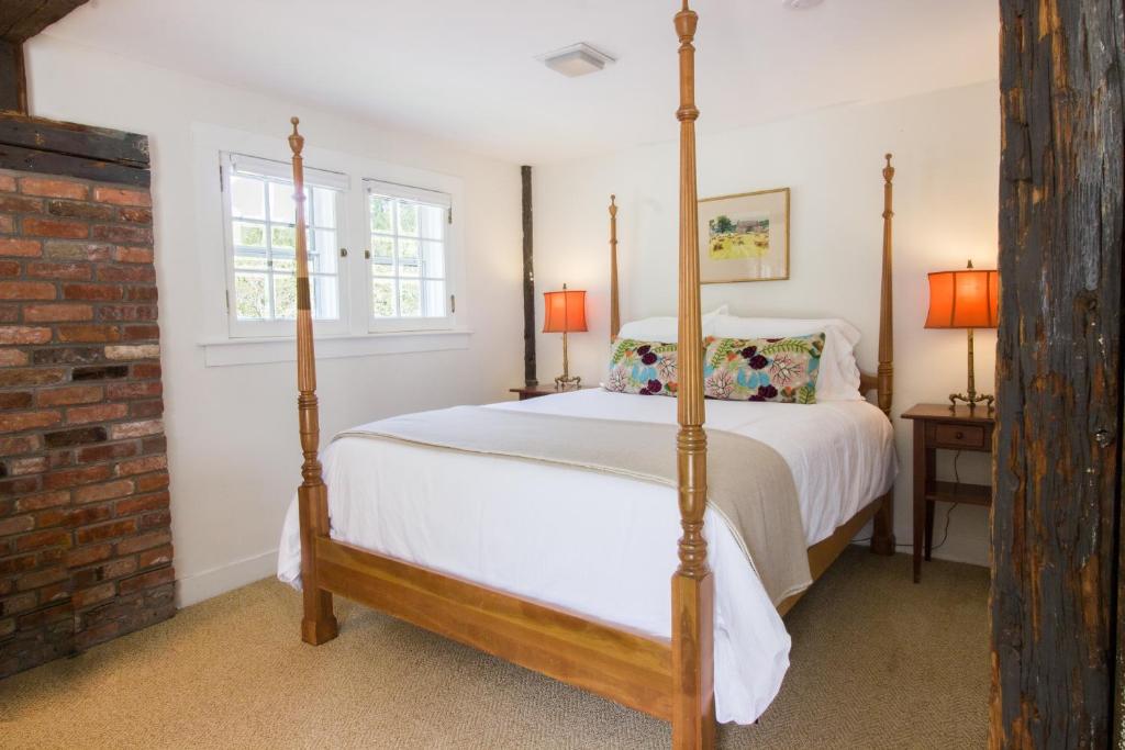a bedroom with a four poster bed and a brick wall at Kedron Valley Inn in Woodstock