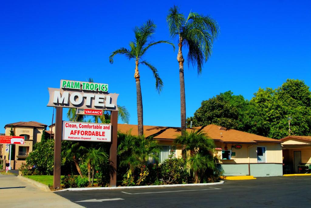un cartel de motel frente a un motel con palmeras en Palm Tropics Motel en Glendora