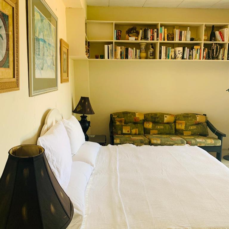 a bedroom with a white bed and a book shelf at Beach Vue Barbados in Bridgetown