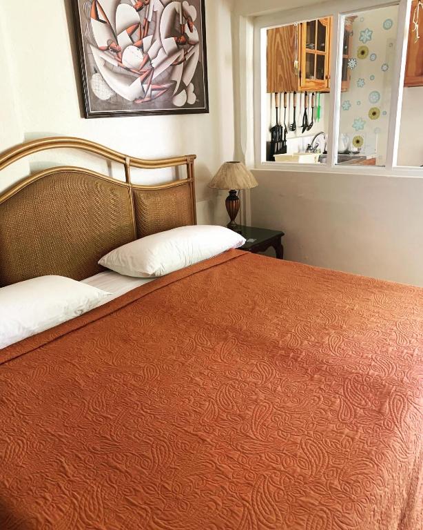 a bedroom with a large bed with an orange blanket at Beach Vue Barbados in Bridgetown