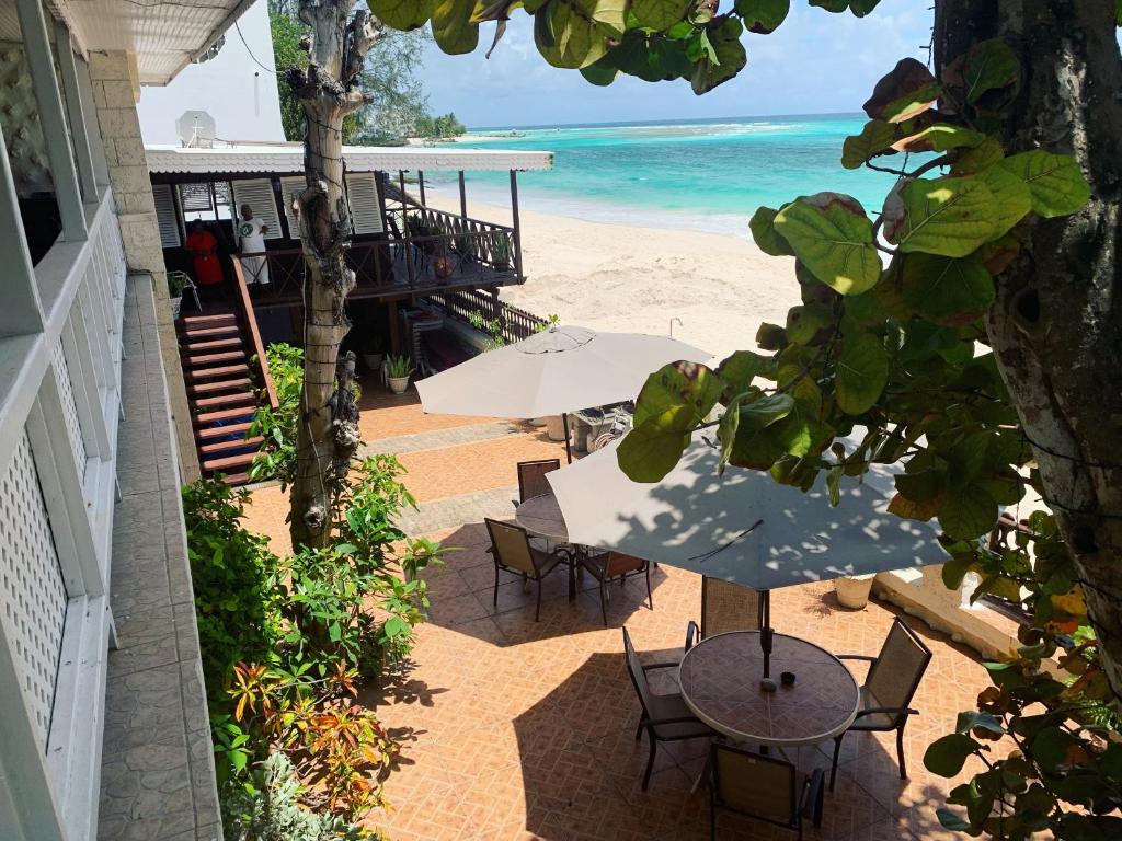 a patio with tables and chairs and the beach at Beach Vue Barbados in Bridgetown