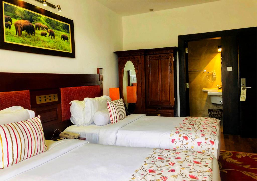 a hotel room with two beds and a bathroom at The Blackpool Resort & Spa in Nuwara Eliya