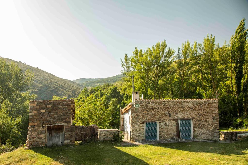 Casa Rural El Huerto de la Fragua في إنسيسو: مبنى حجري قديم بأبواب زرقاء على العشب