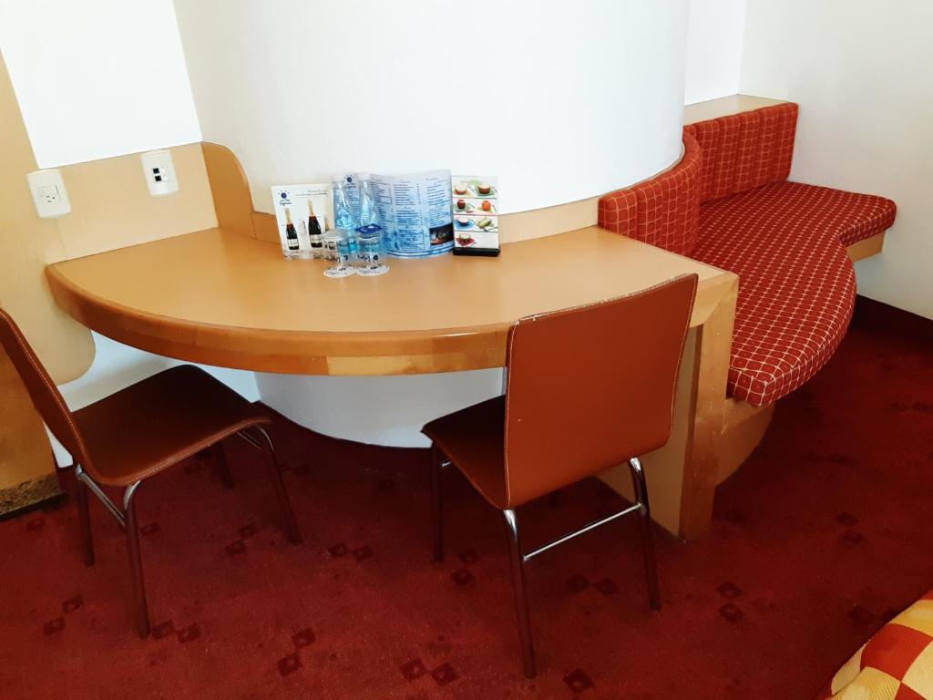 A curved desk with two chairs, bottled water and a built-in upholstered bench.