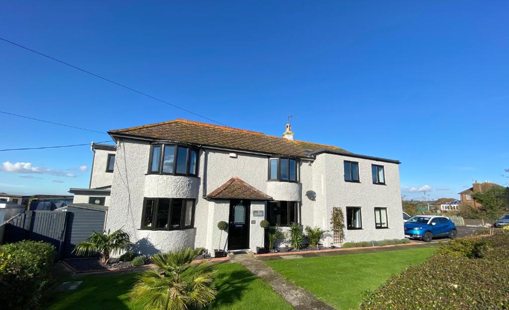 a white house with black windows and a yard at Waterside Guesthouse in Dymchurch