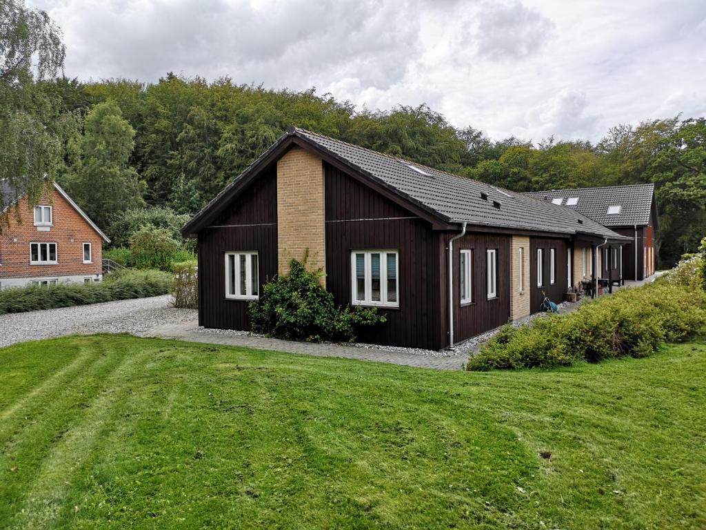 un edificio marrón con ventanas blancas junto a un patio en Klærke Hostel en Skanderborg