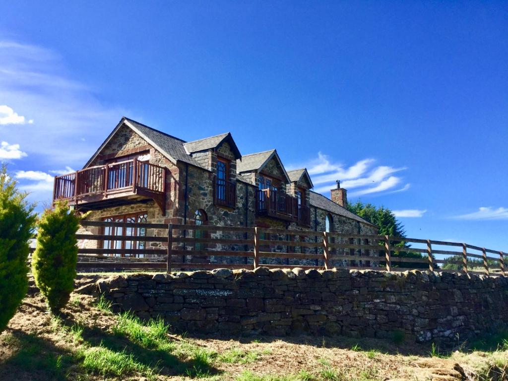 une grande maison au-dessus d'un mur en pierre dans l'établissement Castleview @ Newton Steading Farm, à Kirriemuir