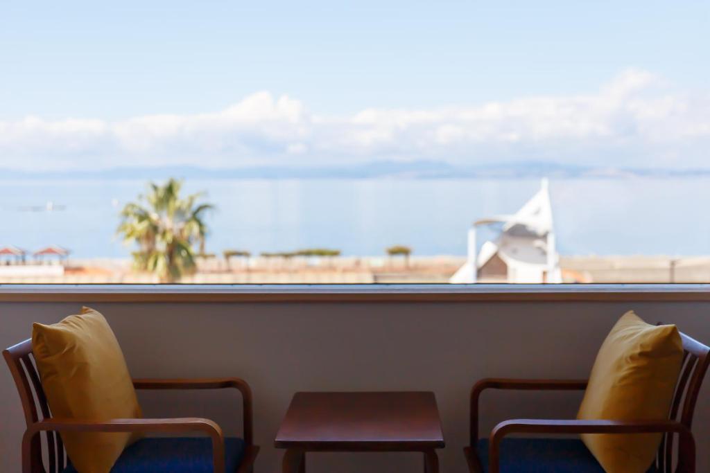 雲仙市にあるIseya, Seaview Private Onsen Bathのビーチの景色を望む客室で、椅子2脚とテーブルが備わります。