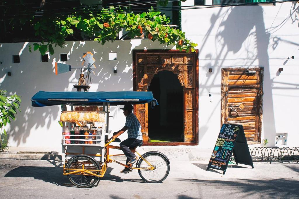 un homme faisant du vélo avec une charrette à provisions dans l'établissement The Green Village Boutique Hotel, à Playa del Carmen