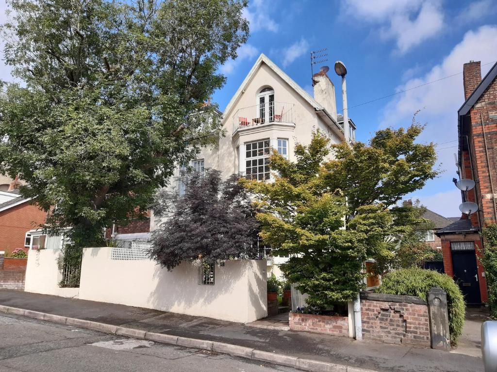 a white house with trees in front of it at Holland House in New Brighton