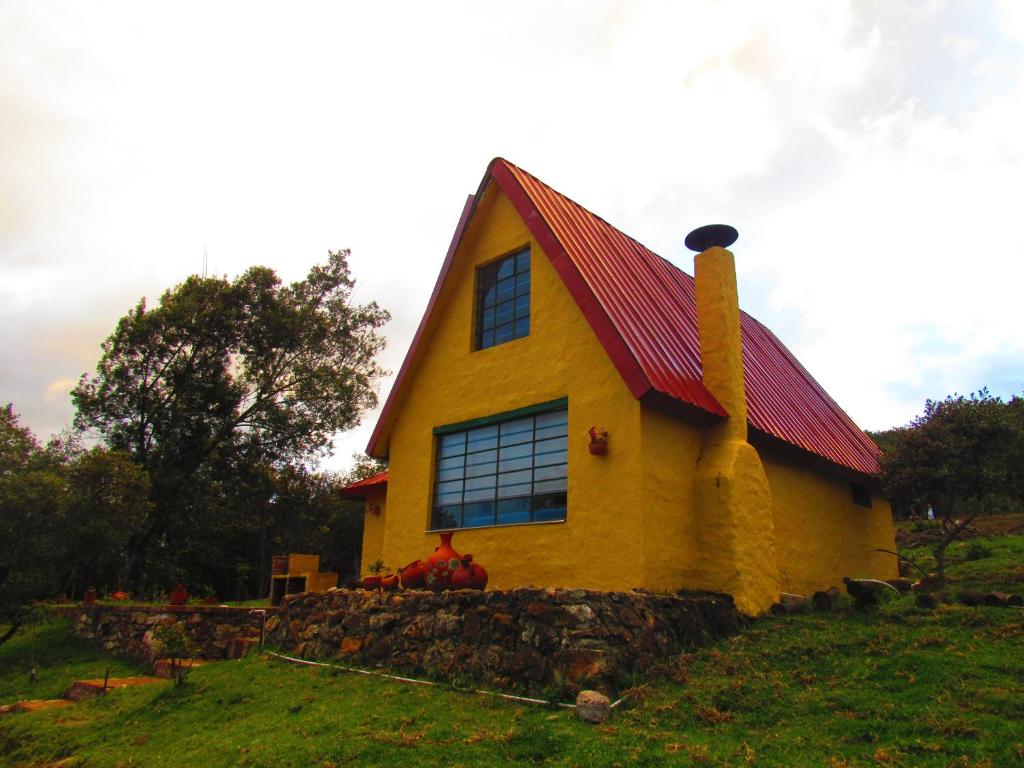 a yellow house with a red roof on a hill at Chalet Guatavita - Tominé. La Casa Amarilla in Guatavita