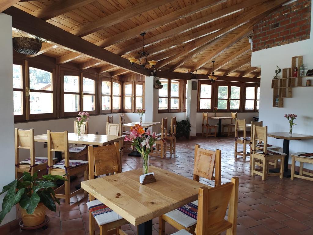 a dining room with tables and chairs and windows at Lunandina Huaraz in Huaraz