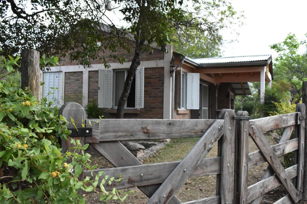 una valla de madera frente a una casa en Cabañas Rayuela y otros cuentos en Santa Rosa de Calamuchita