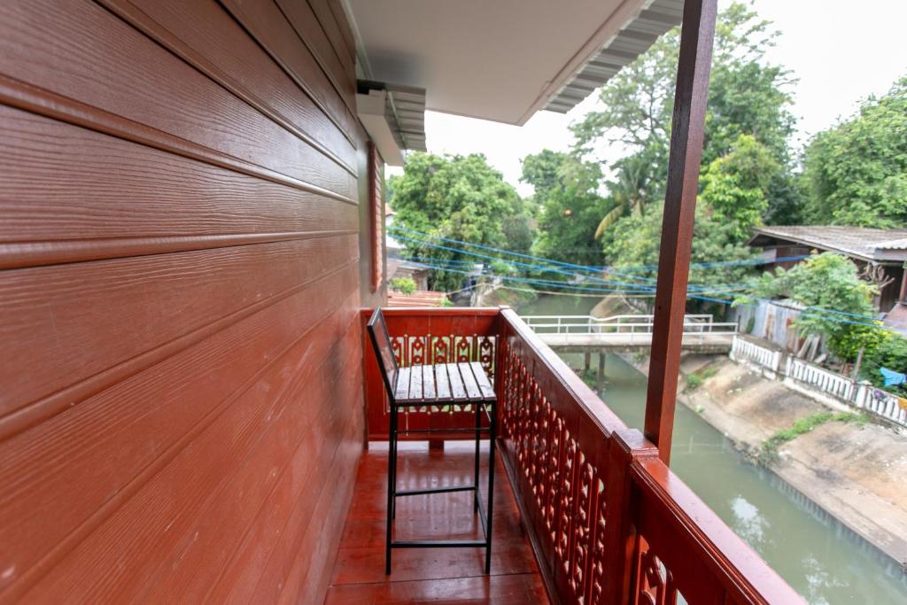 a chair on a balcony with a view of a river at Arku’s House in Chiang Mai