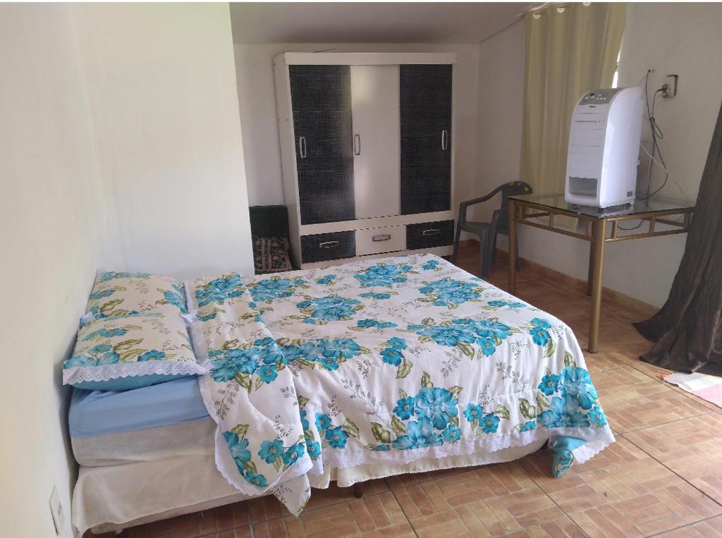 ein Schlafzimmer mit einem Bett und einem Tisch mit einem TV in der Unterkunft Solar boa vista in Congonhas