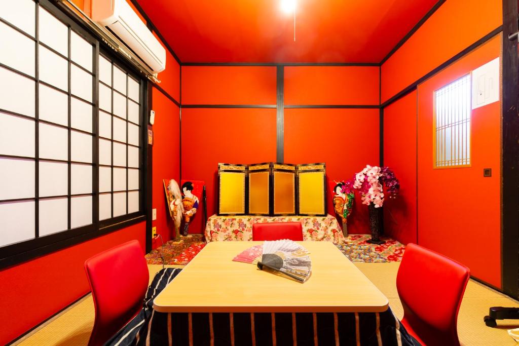 Family house (private house) في أوساكا: غرفة طعام بجدران برتقالية وطاولة وكراسي
