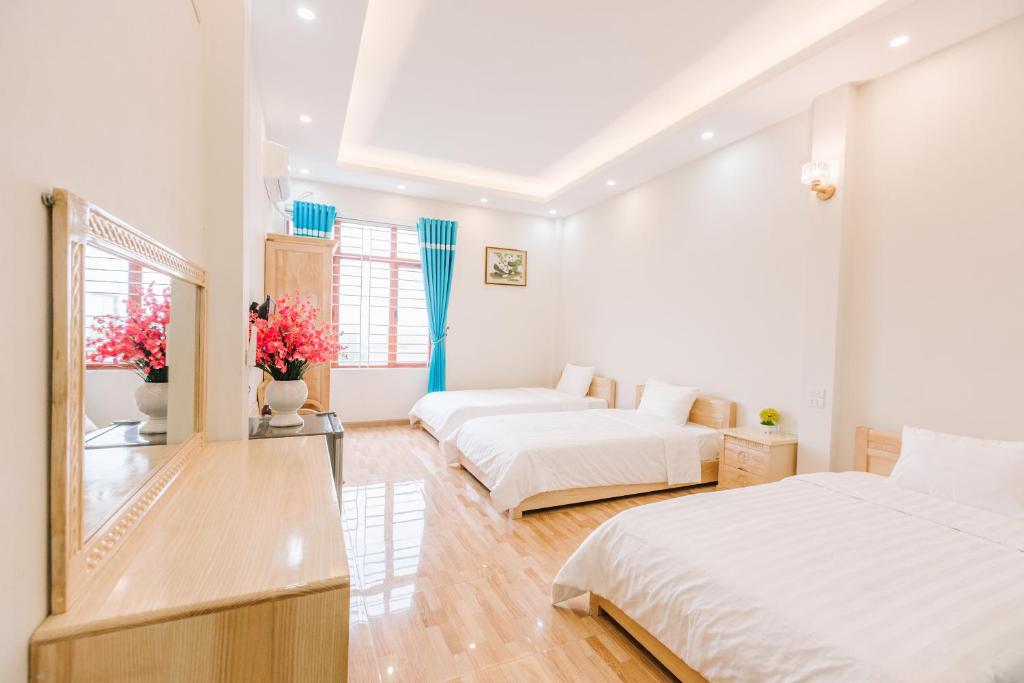 a bedroom with two beds and a table with flowers at La Teisu Airport Hotel in Hanoi