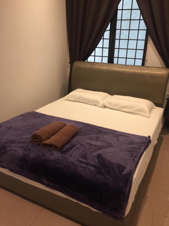 a bed with two towels on it with a window at COMFORTABLE STAY in Ayer Itam