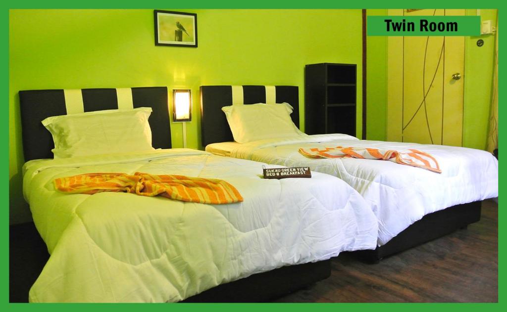 Dos camas en una habitación de hotel con comida. en Sukau Greenview Bed & Breakfast, en Sukau
