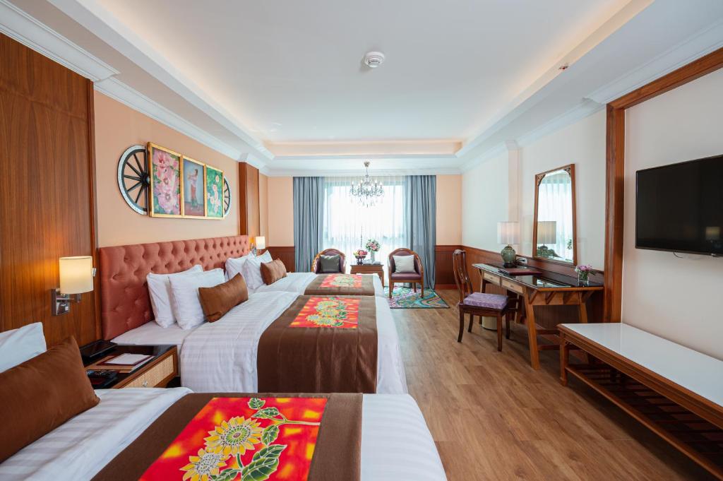 A traditional twin room with two beds, a desk, and a bright window seating area.