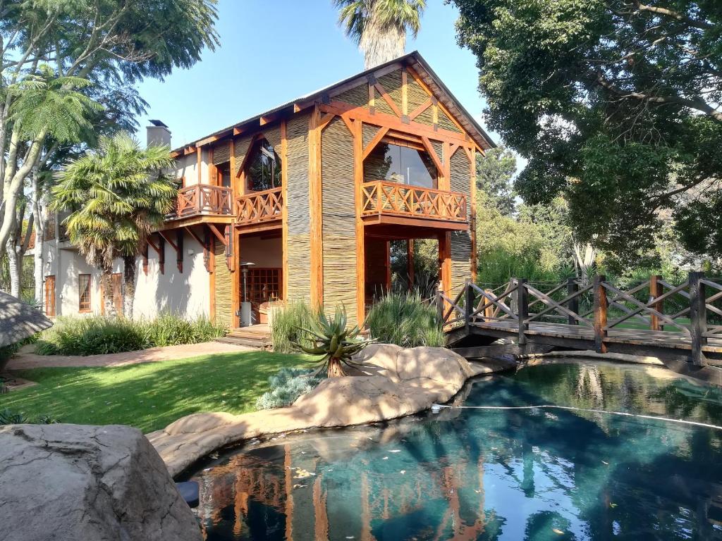 a house with a bridge over a pond at Ikamu's lodge in Germiston