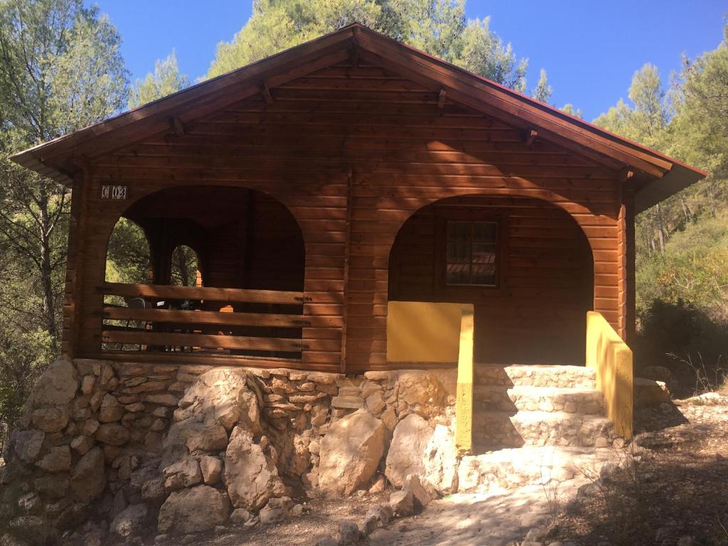 a log cabin with a stone wall at Camping La Puerta in Moratalla