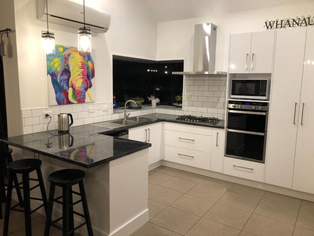 a kitchen with white cabinets and black counter tops at Warm on Waterloo in Palmerston North