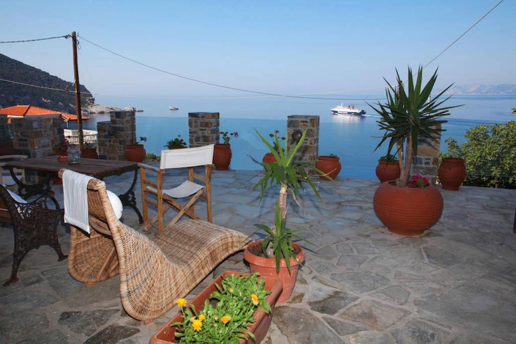 un patio con mesa, sillas y macetas en Studios Milos Skopelos-Where the Sea Meets the Sky, en Skopelos Town
