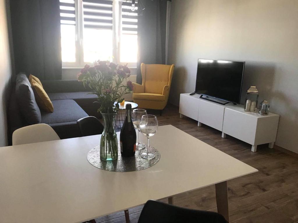 uma sala de estar com uma mesa com copos de vinho e uma televisão em ApartamentLeśna12Hel em Hel