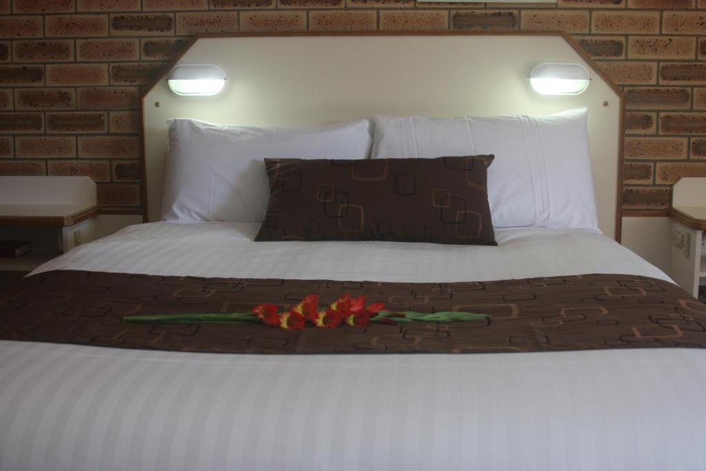 a white bed with a bunch of flowers on it at Garden City Motor Inn in Toowoomba