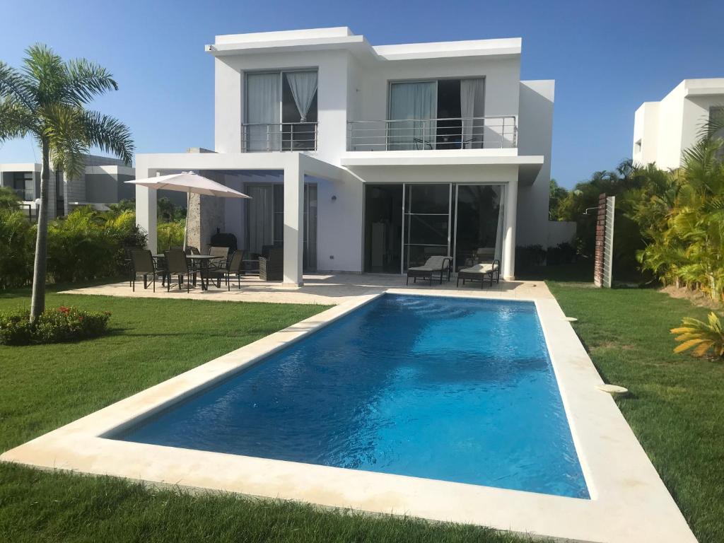 a villa with a swimming pool in front of a house at Villa Real Playa Nueva Romana in La Romana