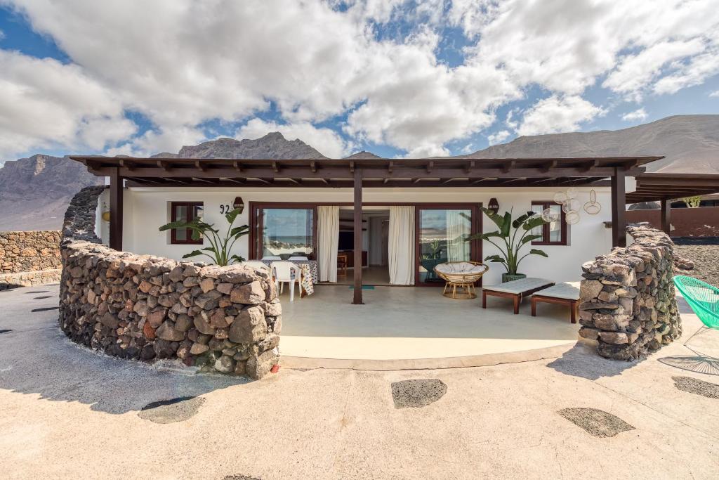 a house with a patio with a stone wall at Villa Taguluche Famara in Famara