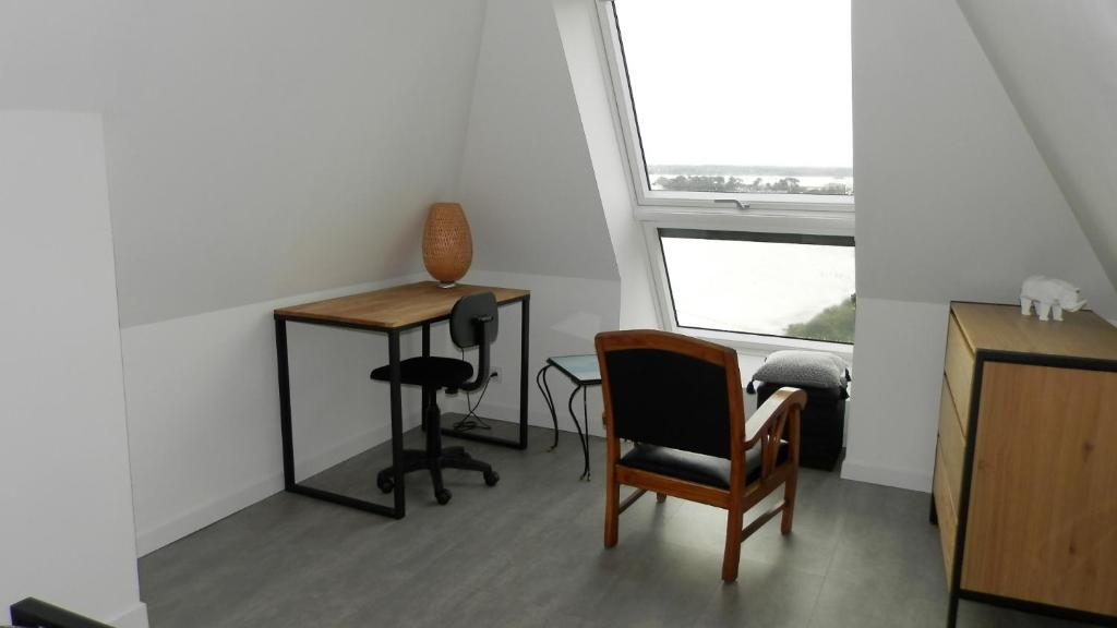 a room with a desk and chairs and a window at Location Tromeal Lasalle in Saint-Pol-de-Léon