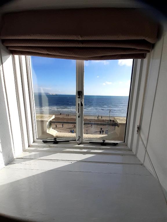 a room with a view of the beach from a window at The Edenhurst Guesthouse in Weymouth