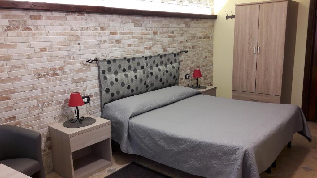 - une chambre avec un lit et un mur en briques dans l'établissement Lamarmora 58, à Sassari