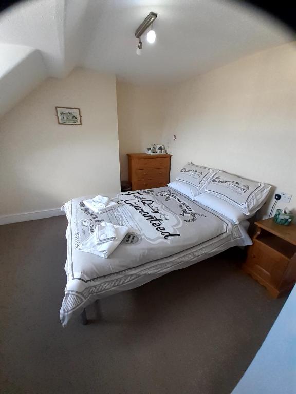 a bedroom with a large bed with white sheets at The Edenhurst Guesthouse in Weymouth