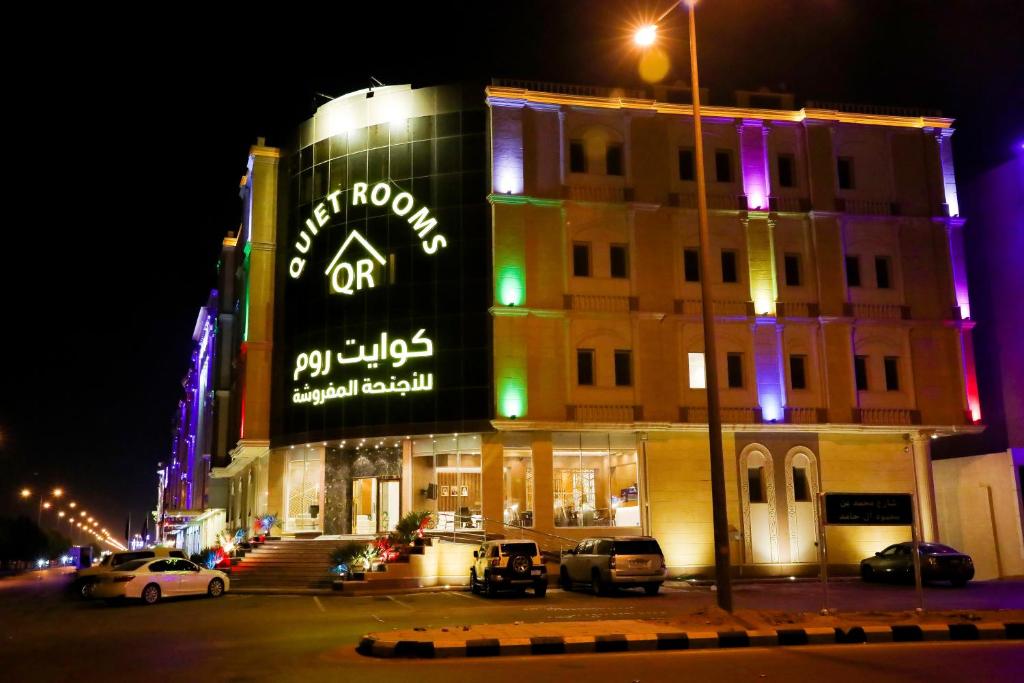 a building with a sign on the side of it at night at Quiet Rooms Suites By Quiet Rooms in Riyadh