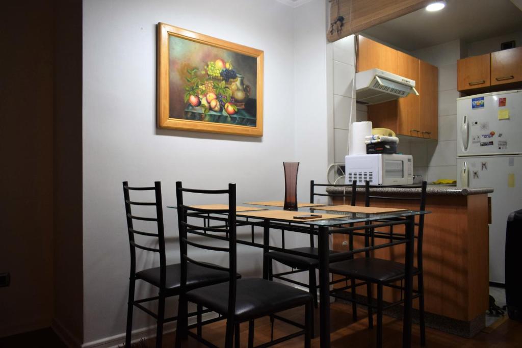 Dpto 1D 1B, Metro Bellas Artes, equipado full con WiFi في سانتياغو: مطبخ مع طاولة مع كراسي و لوحة على الحائط