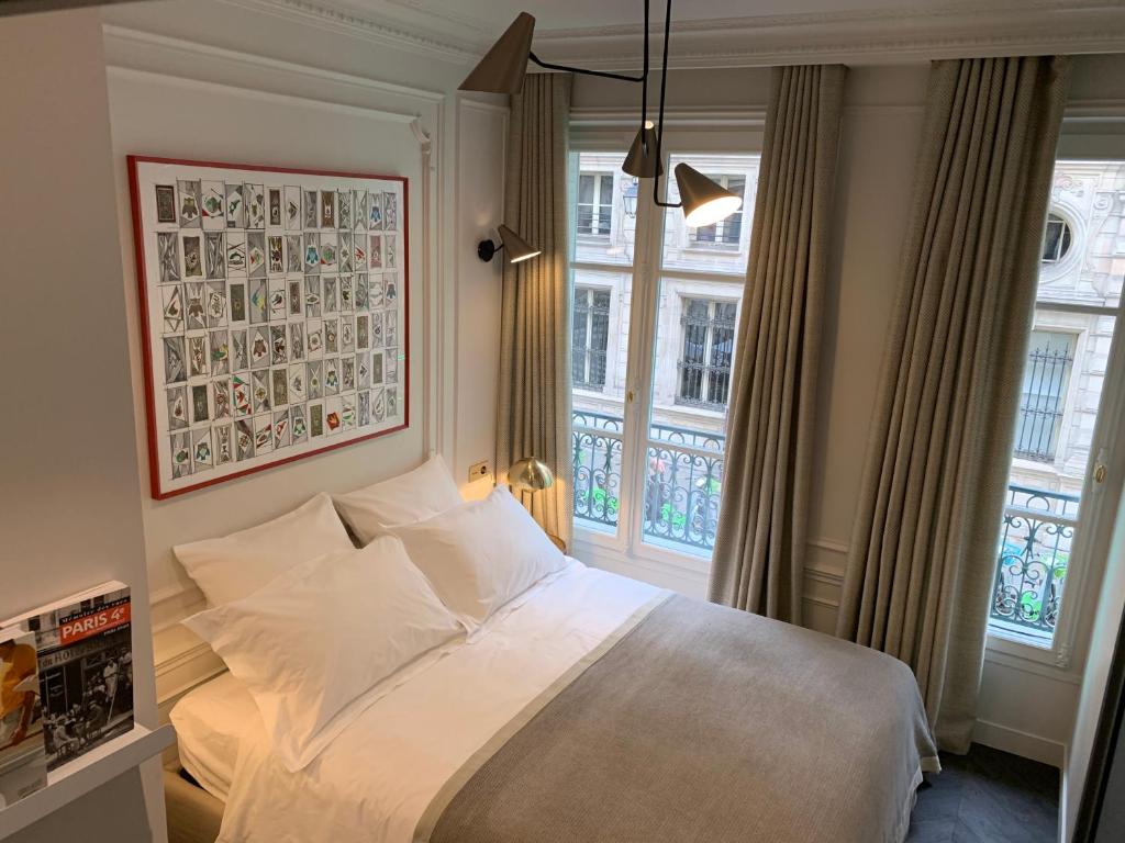 1 dormitorio con 1 cama blanca y 2 ventanas en PARIS RIVOLI NOTRE DAME Chambre d'Hôtes Studio Private en París