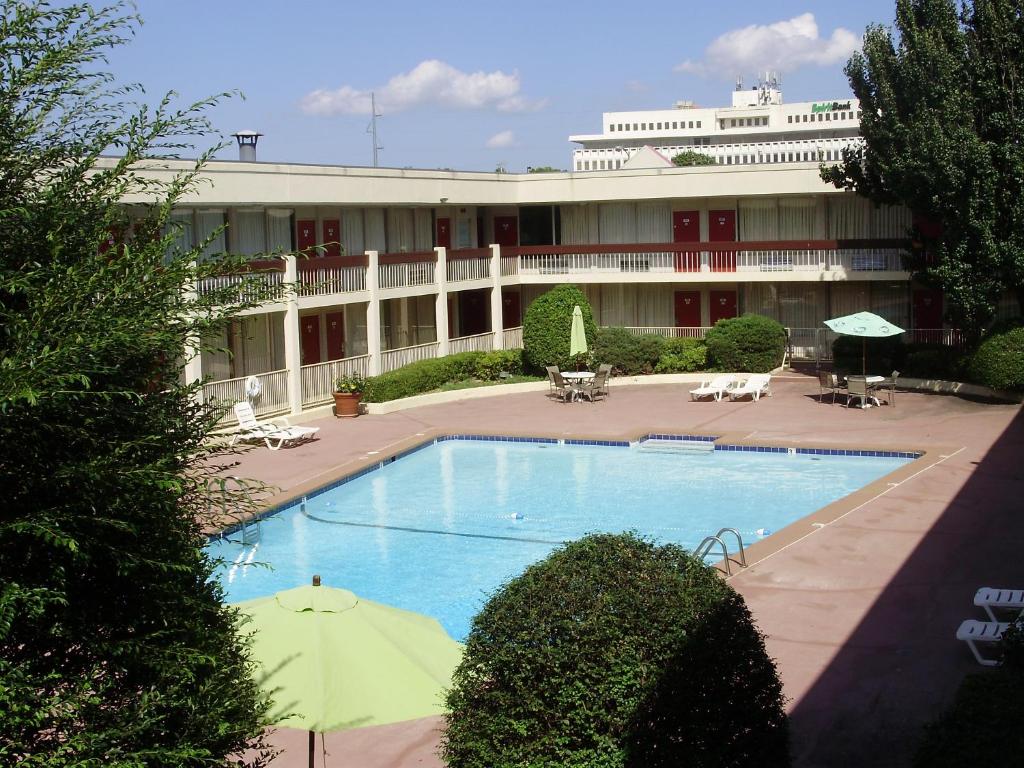 a large building with a swimming pool in front of it at Trade Winds Central Inn in Tulsa