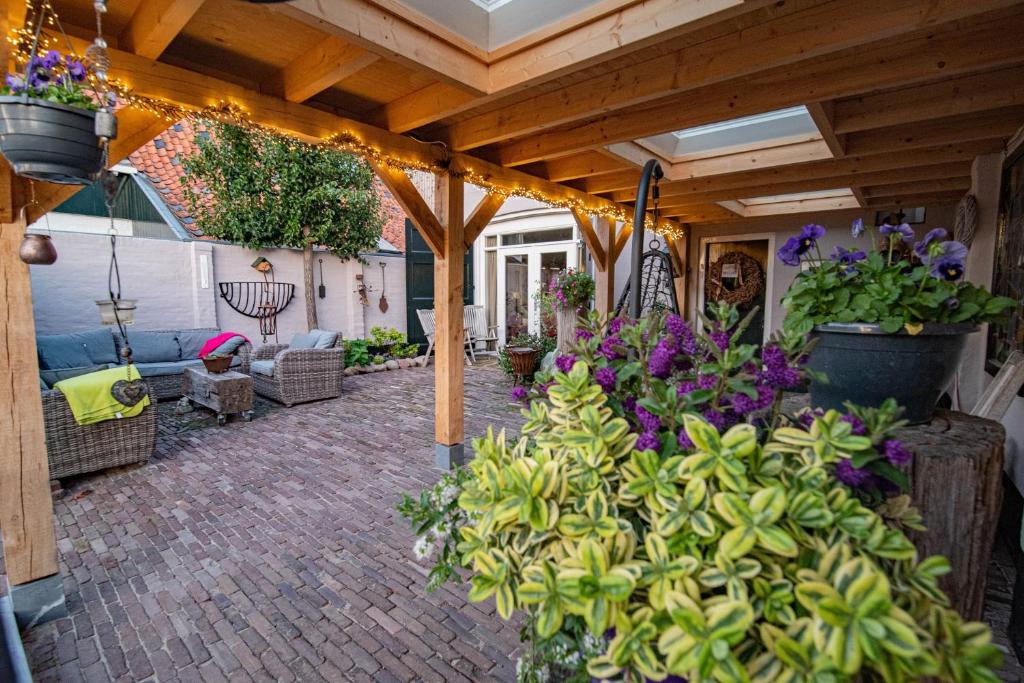 a patio with a wooden pergola with flowers and plants at B&B "de Kleine Vesting" in Elburg