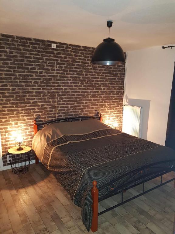 a bedroom with a large bed with a brick wall at Iliade in Rue