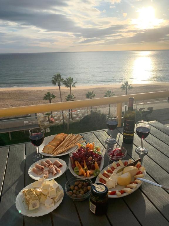 einen Tisch mit Speisen und Weinen und den Strand in der Unterkunft ACR Holiday Apartment in Quarteira